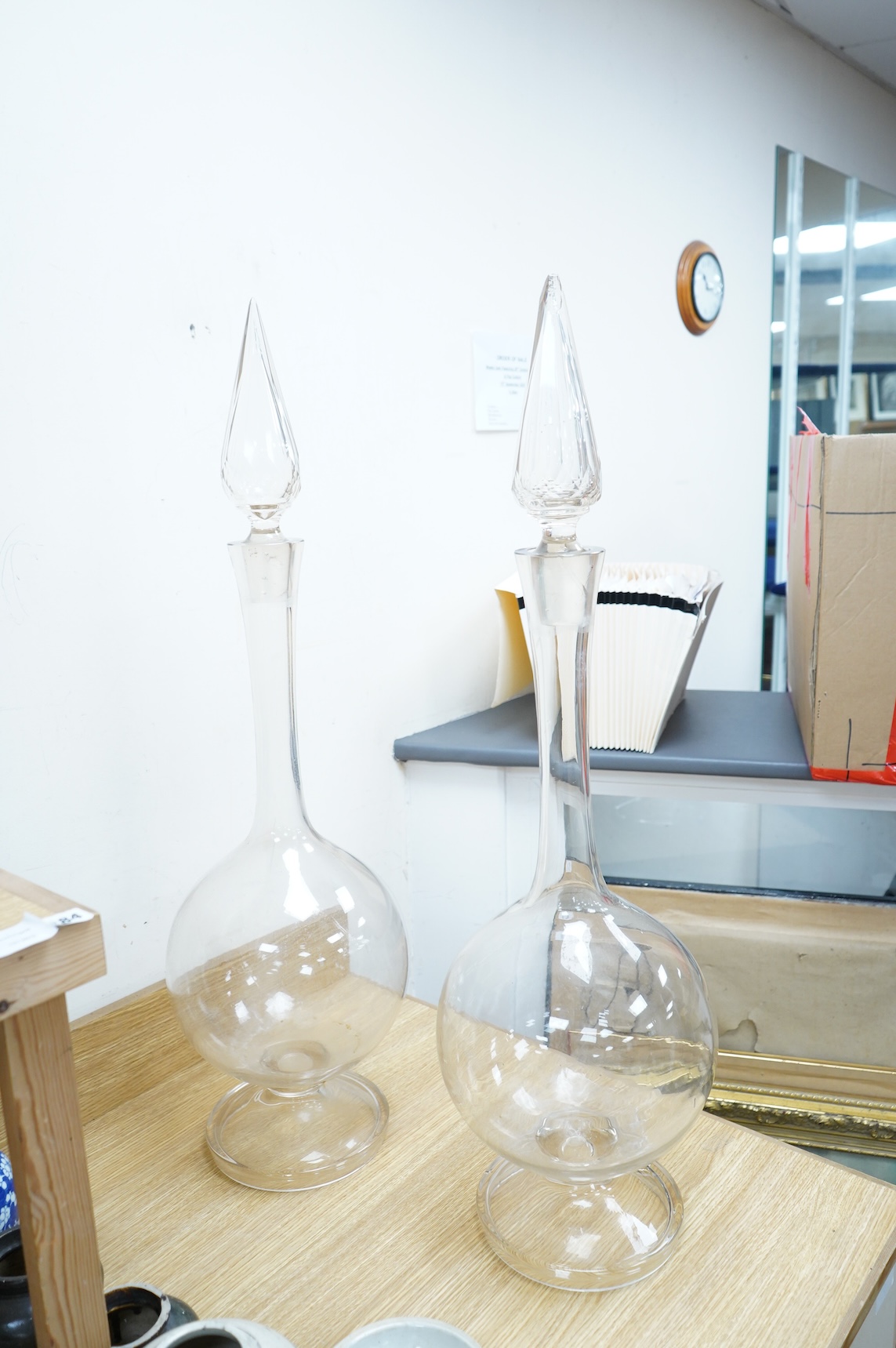 A pair of large clear glass chemist window display bottles and stoppers, one with chip, 90cm high